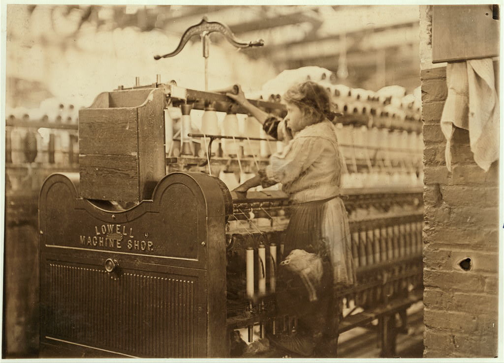 En flicka står uppkliven vid en spinnmaskin i textilfabriken Bibb Mill i Macon, USA.
