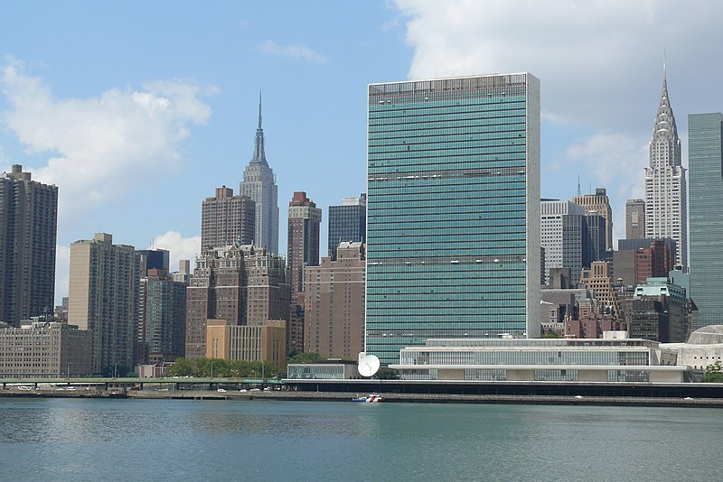 FN:s högkvarter i New York, med det höga sekretariatshuset vid vattnet och stadens byggnader i bakgrunden.